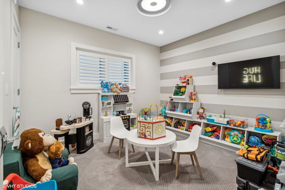 Indoor play area with toys, shelves, table, and chairs.