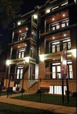 Front view of a multi-story building with balconies and exterior lighting.