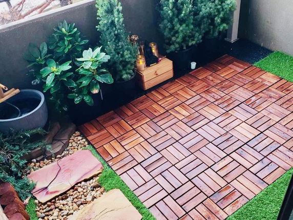 Rooftop area with wooden flooring, potted plants, and decorative stones.