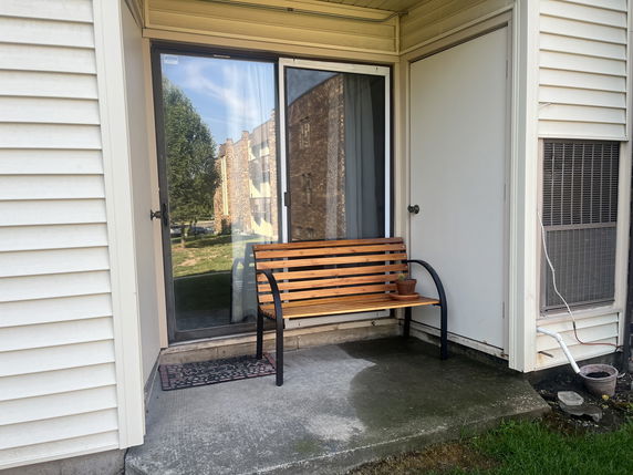 Outdoor area with sliding glass door and a wooden bench.