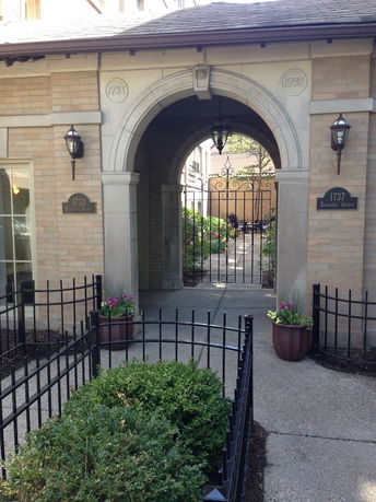 Front view of a building entrance with an arched pathway and brick exterior.