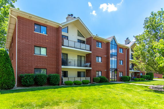 Front view of a multi-story apartment building with brick exterior and balconies.