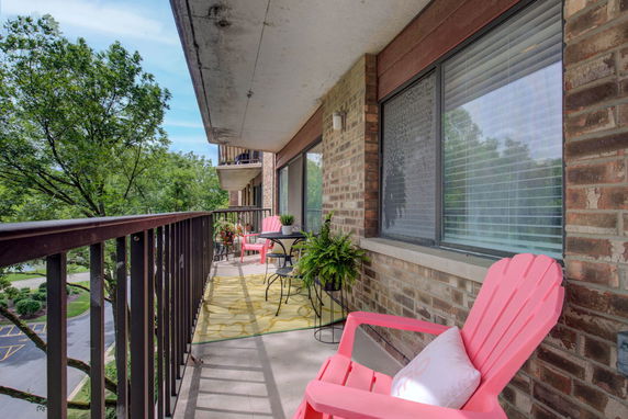 Balcony view with outdoor seating and a view of trees.