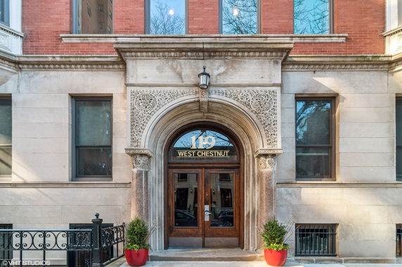 Front view of a building entrance with ornate stonework and wooden doors.