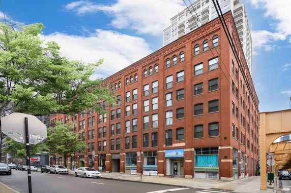 Street view of a red brick multi-story building with large windows.