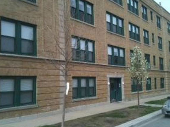 Front view of a multi-story brick building with several windows.