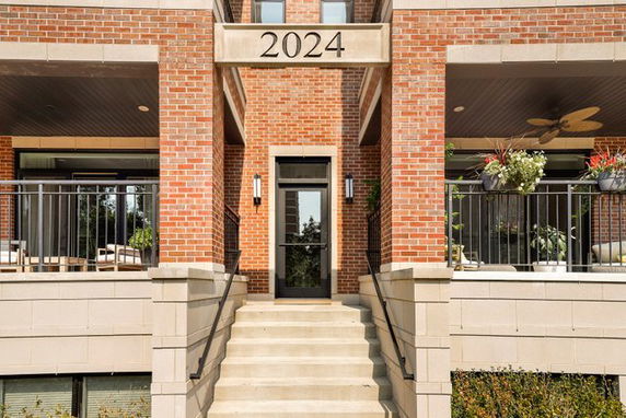 Front view of a brick building with an entrance featuring steps and railings, marked with the number 2024.