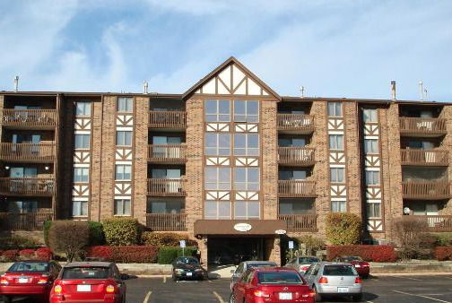 Front view of a multi-story brick apartment building with balconies.