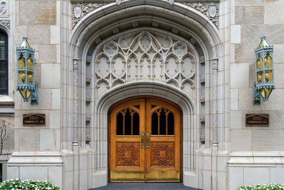 Front entrance of a building with ornate stonework and wooden double doors.