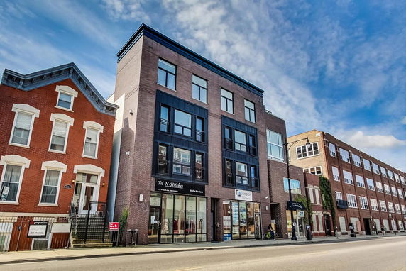Front view of multi-story buildings with brick facades and large windows on a city street.