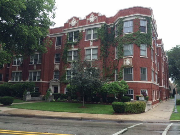 Front view of a multi-story red brick building with ivy-covered walls.