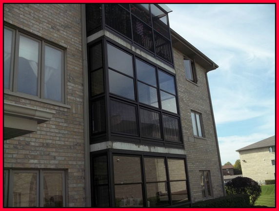 Front view of a multi-story brick building with large windows.