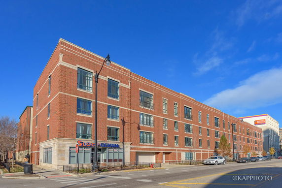 Front view of a multi-story brick building with large windows.