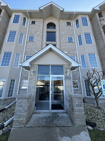 Front view of a multi-story residential building with large windows and a central entrance.