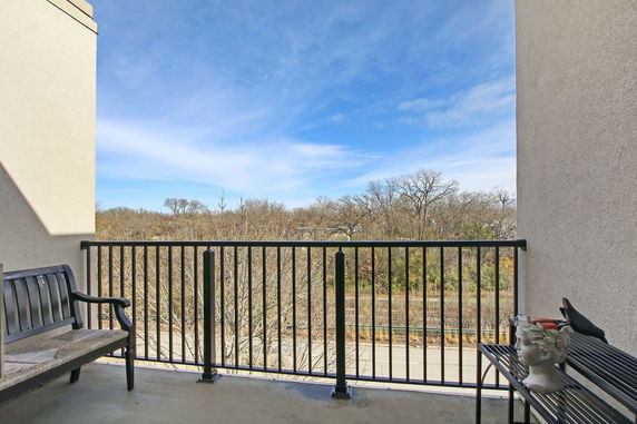 Balcony view overlooking trees and a road in the distance.