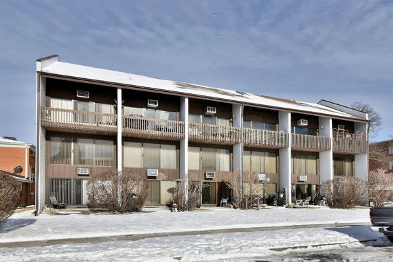 Front view of a multi-story residential building with balconies and large windows, covered in snow.