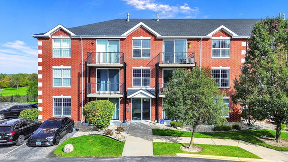 Front view of a three-story brick residential building with balconies.