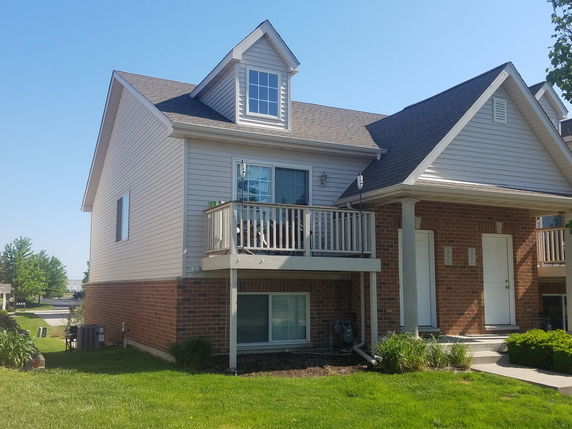 Front view of a two-story house with a balcony and a gable roof.