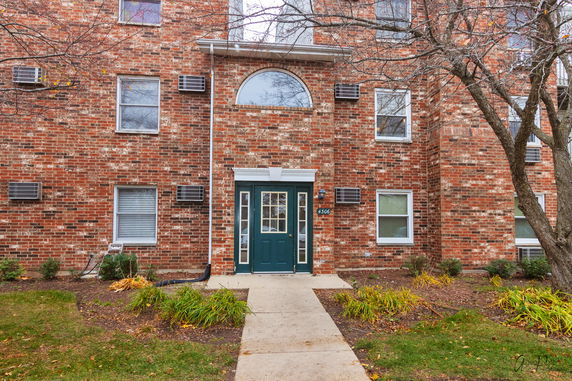 Front view of a brick residential building with multiple windows and a main entrance door.