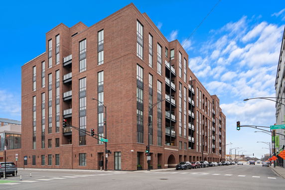 Front view of a multi-story brick building with large windows and balconies.