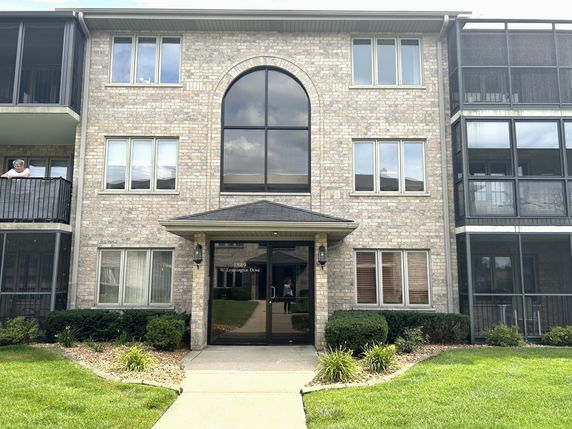 Front view of a three-story apartment building with balconies and large windows.