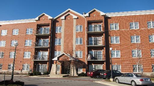 Front view of a multi-story brick apartment building with balconies.