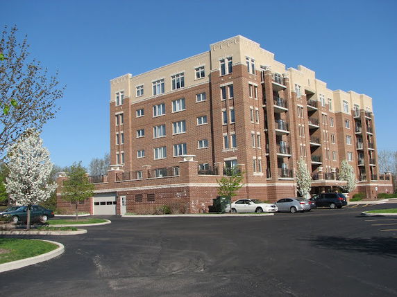 Front view of a multi-story brick apartment building with parking spaces.
