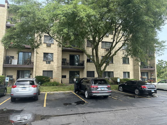 Front view of a multi-story residential building with balconies and parking area.