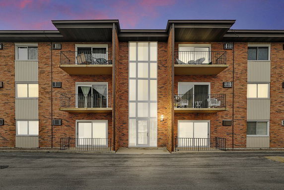 Front view of a multi-story brick apartment building with balconies.