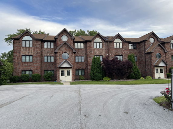 Front view of a multi-story brick building with multiple windows and a gabled roof.