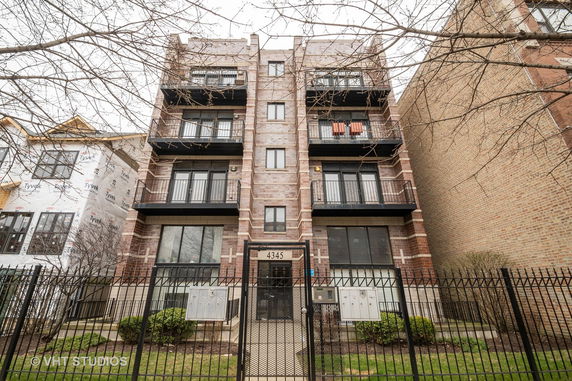 Front view of a multi-story apartment building with balconies and a gated entrance.