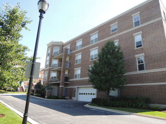 Front view of a four-story brick apartment building with balconies.