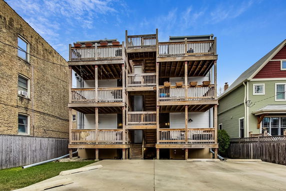 Back view of a multi-story building with wooden balconies and outdoor stairs.
