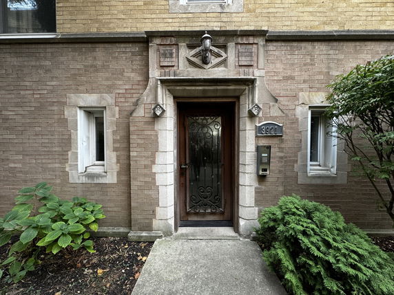 Front view of a brick building entrance with decorative elements around the door.