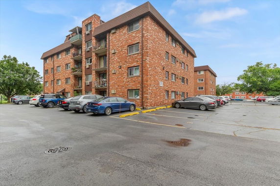 Outdoor parking area adjacent to a multi-story brick building.