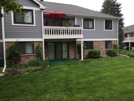 Front view of a two-story house with a balcony and a mix of brick and siding exterior.