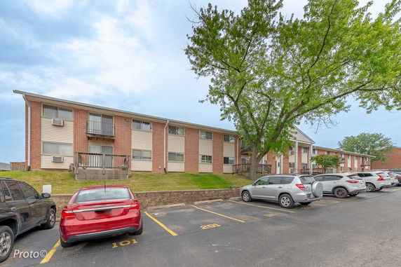 Front view of a two-story apartment building with parking spaces.