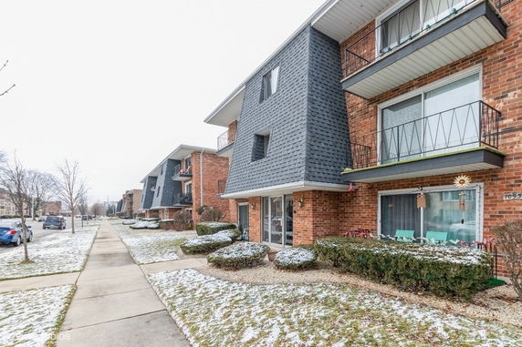 Front view of a multi-story brick apartment building with balconies.