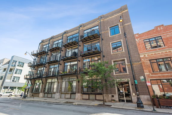 Front view of a multi-story building with balconies and large windows.