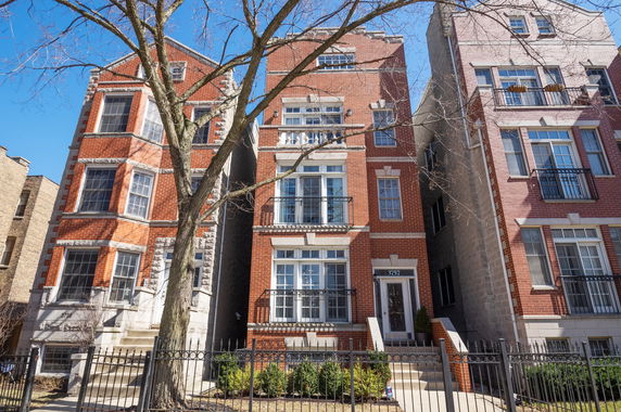 Front view of a multi-story brick building with bay windows and balconies.