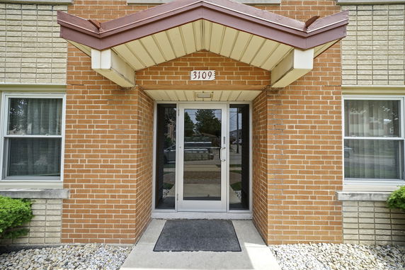 Front view of a brick building entrance with a glass door and awning.