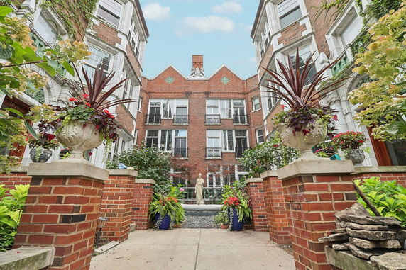 Front view of a brick residential building with ornate windows and decorative planters.