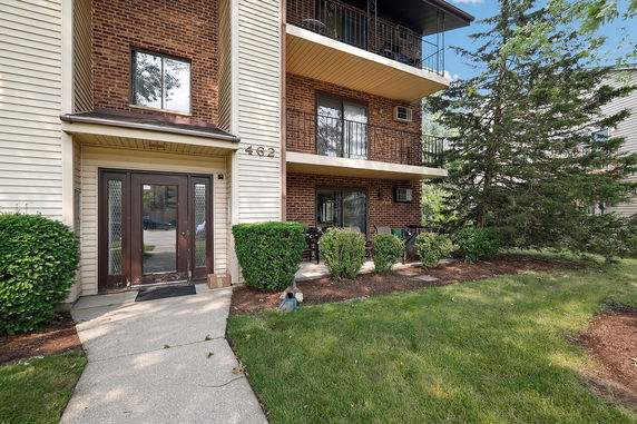 Front view of a multi-story building with brick and siding exterior, balconies, and a double door entrance.