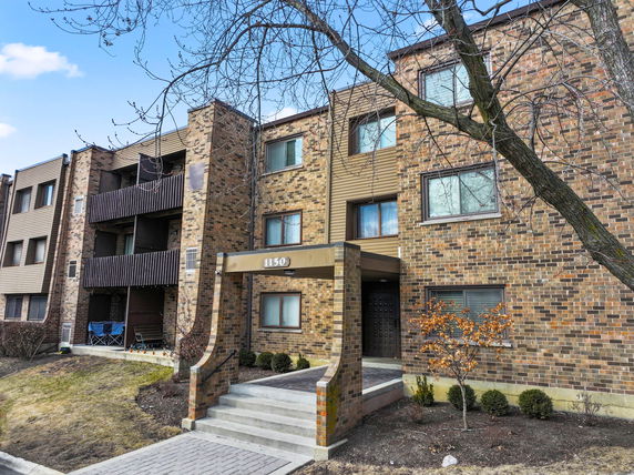 Front view of a multi-story brick apartment building with balconies.