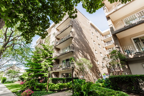 Front view of a multi-story apartment building with balconies and brick exterior.