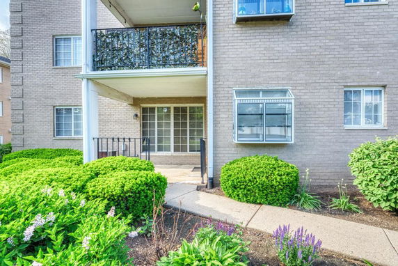 Front view of a building entrance with sliding glass doors and a covered balcony.