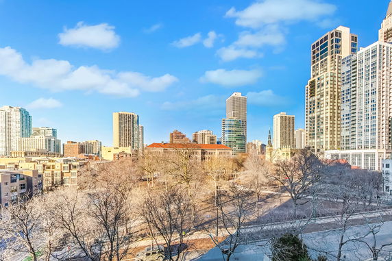 Panoramic view of a city skyline with tall buildings and bare trees.