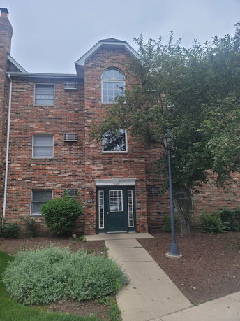 Front view of a brick apartment building with multiple floors and a central entrance.