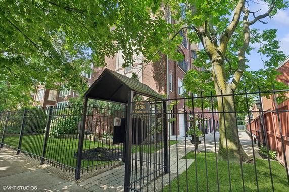 Front view of a multi-story brick building with a gated entrance.