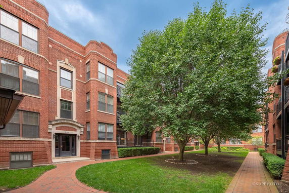 Front view of a multi-story brick apartment building with a courtyard.